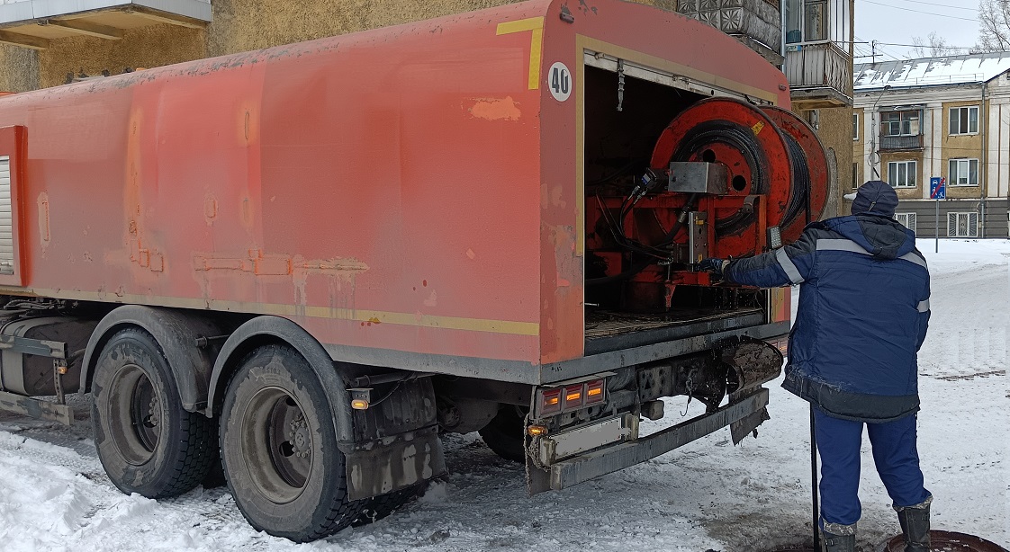 Каналопромывочная машина и работник прочищают засор в канализационной системе в Олекминске